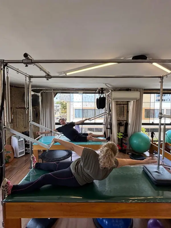 Aula no cadillac e no reformer, com a cidade vista pela janela ao fundo.